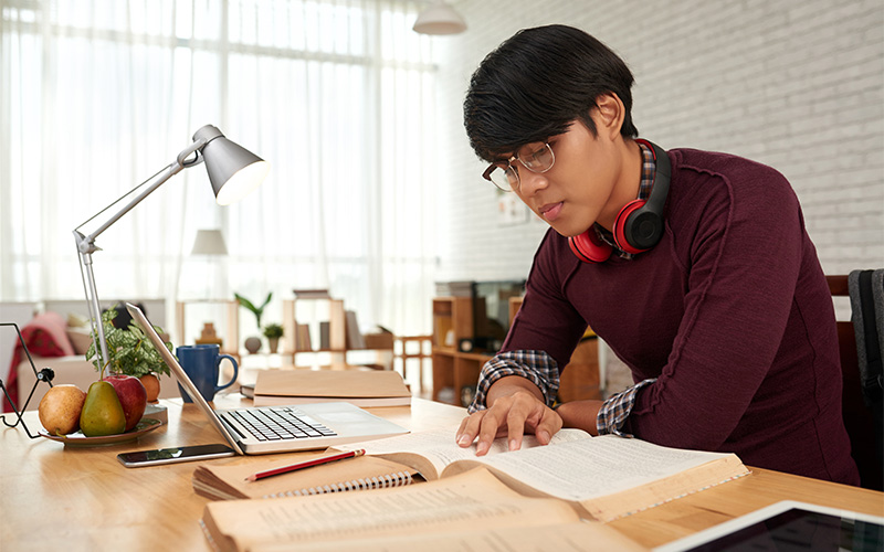 a student in a quiet study space reviewing IB textbooks and notes